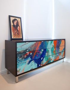 a painting is on top of a dresser in a room with white walls and flooring