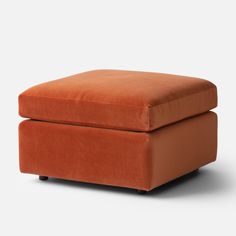 an orange footstool sitting on top of a white floor