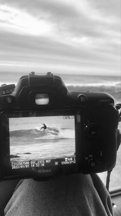 a person is holding up a camera to take a picture of the ocean with a surfboard