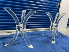 two clear glass vases sitting on top of a blue cloth covered floor next to a roller door