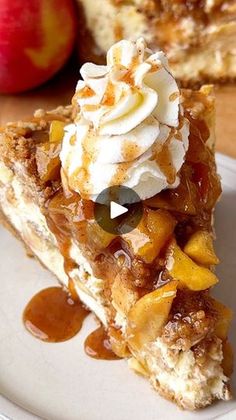 a piece of pie with whipped cream and fruit on top sits on a plate next to an apple