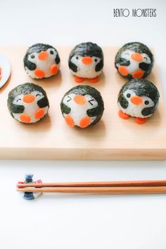 there are some little penguins made out of sushi and chopsticks on the table