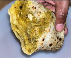 a hand holding a piece of food on top of a plate