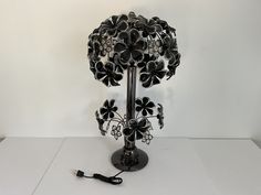 a black and white lamp with flowers on it sitting on a table next to a charger