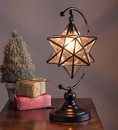 a table lamp with a star on it next to a small christmas tree and presents