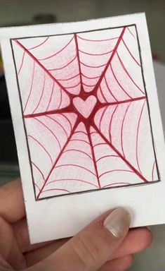 a hand holding up a piece of paper with a spider web design on it