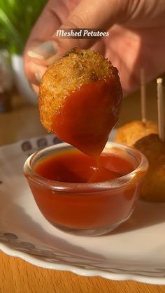 a person dipping something into a small bowl on a plate with other food items in the background