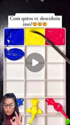 a woman is holding her hand up in front of an art board with different colored paint