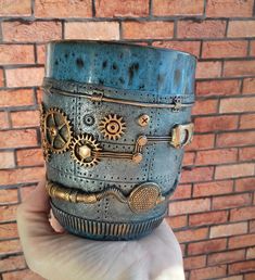 a hand holding a blue cup with gears on it