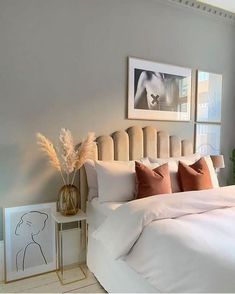 a bed with white sheets and pillows in a bedroom next to a painting on the wall