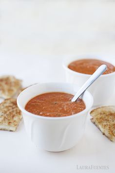 two white bowls filled with soup next to crackers