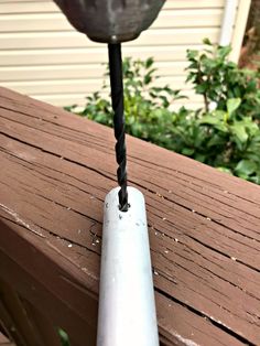 a drill is being used to fix a piece of wood on a deck outside with bushes in the background