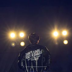 a man standing in front of a stage wearing a black leather jacket with the words don't care 300 a thing on it