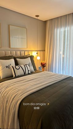 a bed with two pillows and some pictures on the wall above it in front of a window