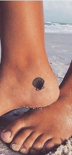 a woman's foot with a shell tattoo on it