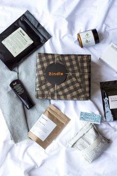 the contents of a travel bag laid out on a bed with some skin care products