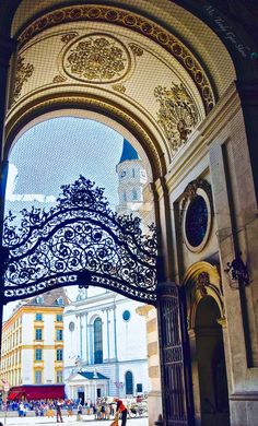 an ornate iron gate in the middle of a building with people walking around it and onlookers