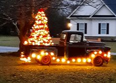 a truck with lights on it parked in front of a christmas tree and house at night