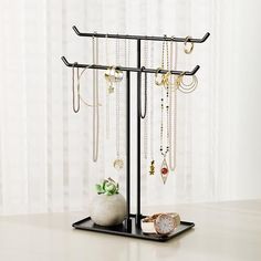 a jewelry stand with several necklaces hanging from it's sides and a watch on the other side