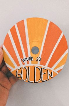 someone is holding up a yellow and orange frisbee with the words you're so golden on it