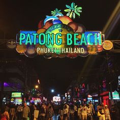 people are walking under the sign for patong beach phoket thailand at night