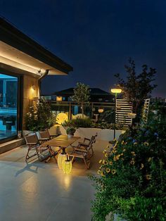 an outdoor patio with chairs and table at night