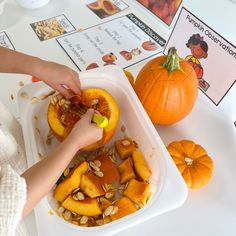 a child is peeling the inside of a pumpkin in a bowl with seeds on it