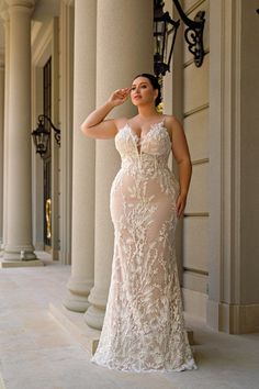 a woman in a white dress standing next to columns