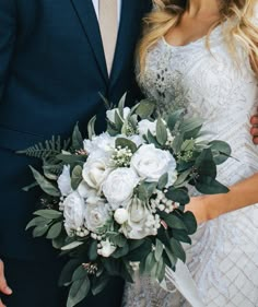 a bride and groom pose for a wedding photo in front of the camera with their bouquet