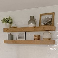 two wooden shelves with pictures, vases and other items on them in a bathroom