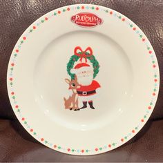 a white plate with a santa clause on it and a reindeer holding a wreath around its neck