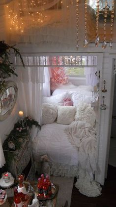 a bedroom with white bedding and lots of lights on the windowsill, decorated for christmas