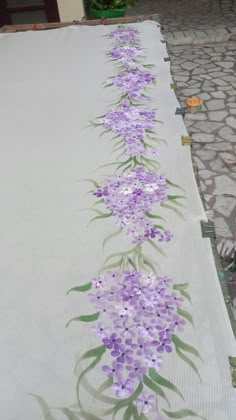 purple flowers are painted on the side of a white tablecloth that is laid out