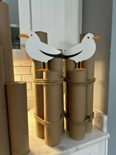 two seagulls are standing on top of rolled up toilet paper and wrapped in twine