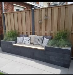 a wooden bench sitting on top of a cement slab next to a green lawn and fence