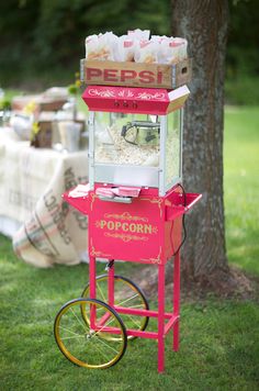 an old fashioned popcorn vending machine is on display in the grass near a tree