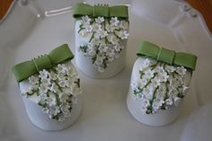 three white vases with green bows and flowers on the top one is filled with baby's breath