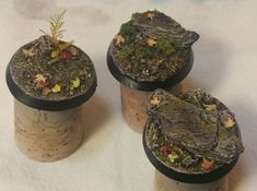 three corks with plants growing out of them on a white cloth covered tablecloth