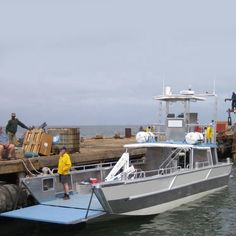 several people are loading and unloading cargo onto a boat in the water at a dock