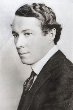 an old black and white photo of a man in a suit with his hair pulled back