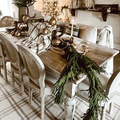 a dining room table with christmas decorations and greenery on the top, surrounded by chairs