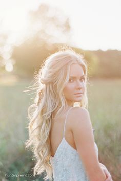 a beautiful blonde woman standing in a field