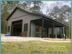 a garage with an attached carport and covered in metal siding, surrounded by trees