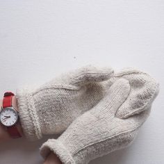 a woman's hand with a wrist watch and mittens on her arm