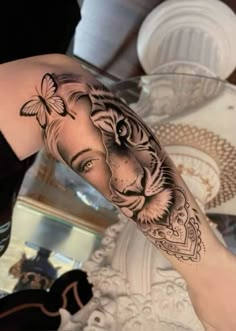 a woman with a tiger and butterfly tattoo on her arm is shown in front of a mirror