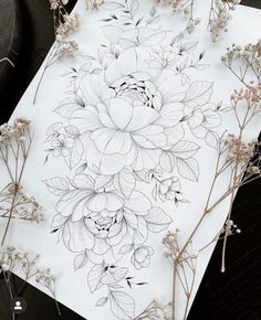 some flowers are sitting on top of a piece of paper with pencils and ink