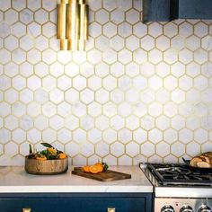 a kitchen with an oven, counter top and gold accents on the backsplash