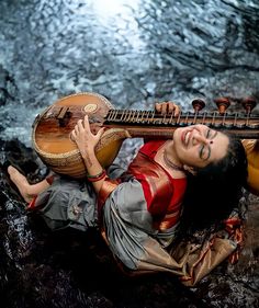 a woman laying on the ground holding a musical instrument