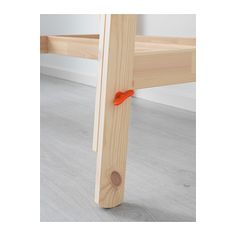 a wooden bed frame with an orange ribbon on the end and two rails attached to it