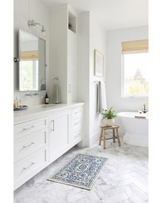 a bathroom with white cabinets and marble floors